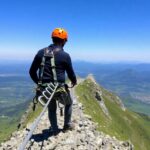 Via ferrata climber on a rocky mountain path with cables.